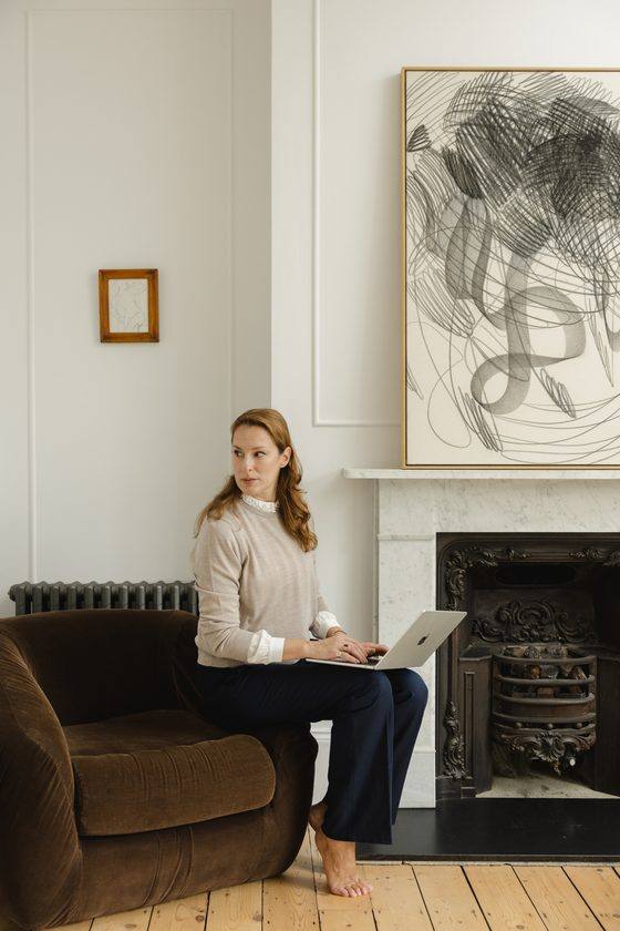 Anastasia Roumelioti working at a laptop beside a marble fireplace